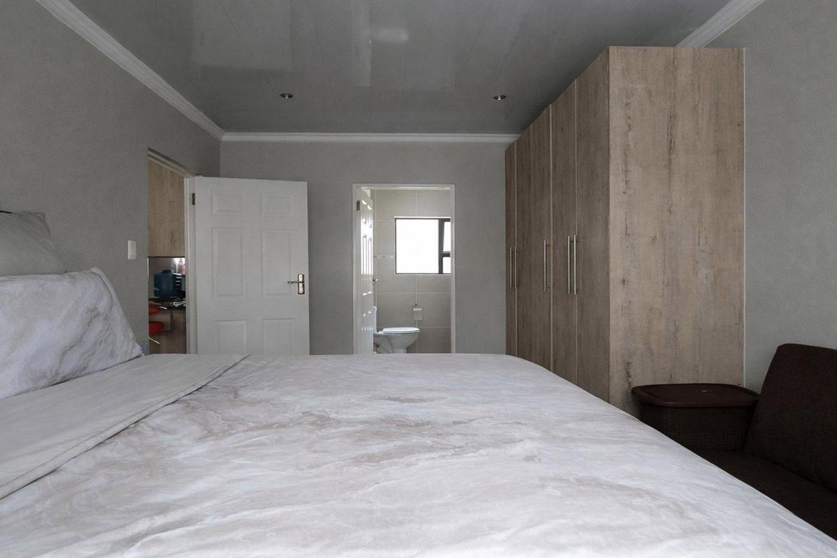 A well-maintained bedroom featuring built-in wooden cupboards, recessed ceiling lighting, and direct access to an en-suite bathroom.