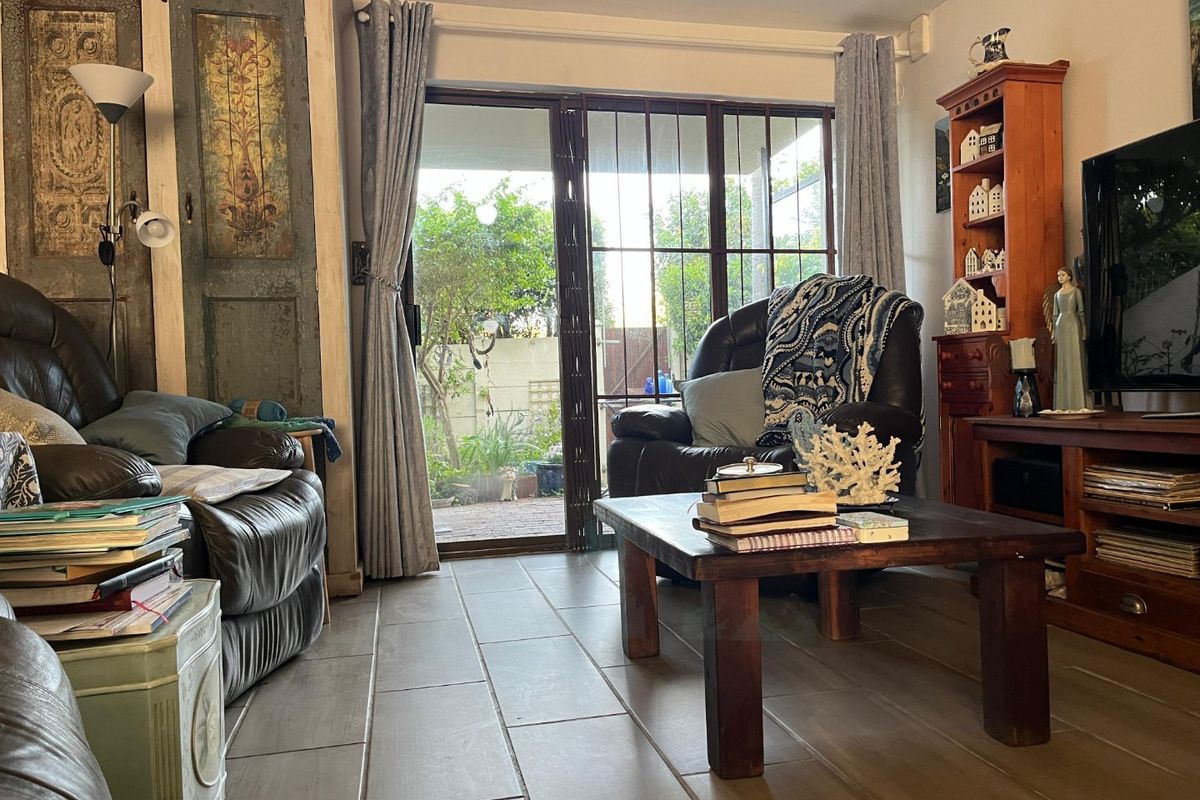 A living room featuring tiled flooring and a sliding glass door with a security gate, providing direct access to the outdoor area.