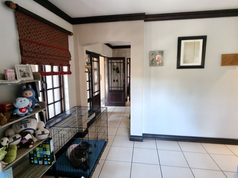 A bright hallway featuring tiled flooring, dark timber crown molding, and classic leaded glass doors leading to adjacent rooms.