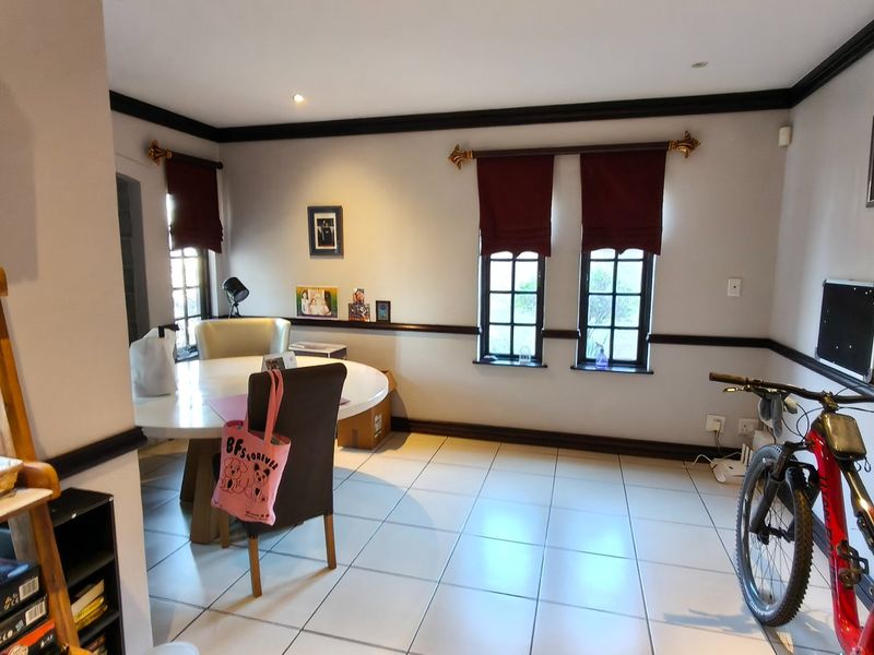 A living area featuring tiled flooring, crown molding, chair rail detailing, and multiple casement windows providing natural light.
