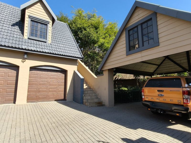 Exterior view of a property featuring a double garage, a covered carport, and an external staircase leading to an upper level.