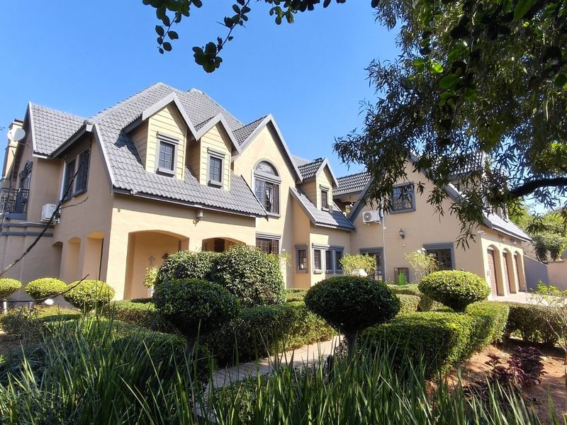 A well-maintained double-story residence featuring a classic architectural design with dormer windows, a tiled roof, and a manicured front garden.