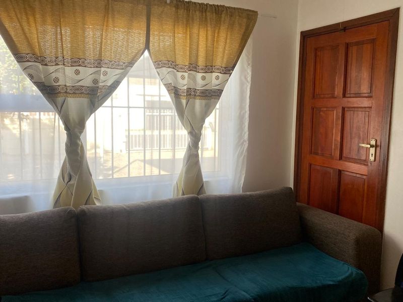A living area featuring a window with security bars and a traditional timber panel door.