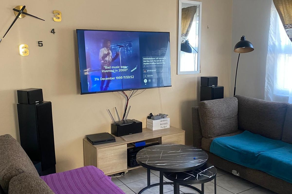 A living room featuring tiled flooring and a wall-mounted television setup with visible wiring.