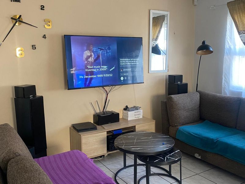 A living room featuring tiled flooring and a wall-mounted television setup with visible wiring.