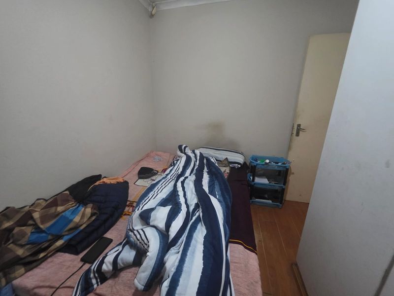 A compact bedroom featuring laminate flooring and plain walls, requiring cosmetic updates to improve its overall presentation and appeal.