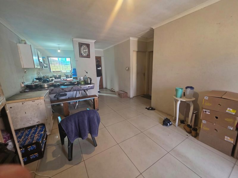 Open-plan living and kitchen area featuring tiled flooring and basic built-in cabinetry, offering a functional space with potential for modernization.