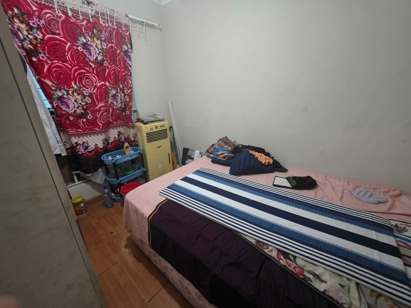 A compact bedroom featuring laminate flooring and a built-in wardrobe, requiring cosmetic updates to improve its overall appeal.