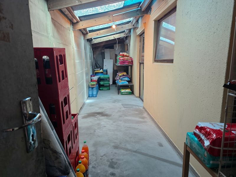 A functional utility or storage area featuring a concrete floor, masonry walls, and a translucent roof structure providing natural light.