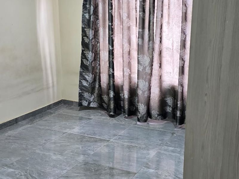 An empty bedroom featuring grey tiled flooring, recessed downlighting, and coved cornicing, with visible wall staining requiring attention.