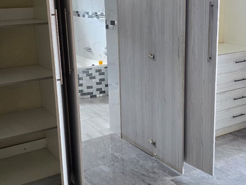 Bedroom featuring modern grey marble-look floor tiles and extensive built-in cabinetry with direct access to an en-suite bathroom.