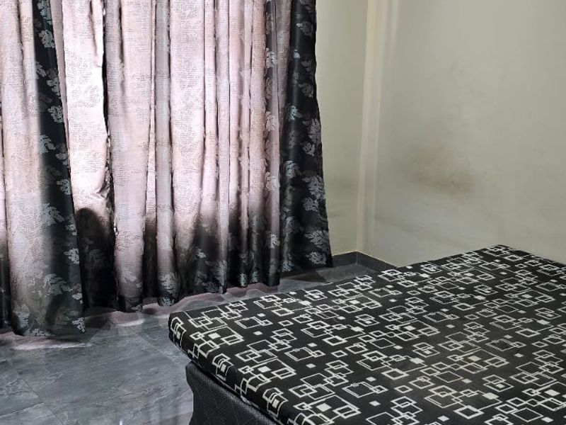 A bedroom featuring tiled flooring, recessed lighting, and coved ceilings. The walls show visible signs of staining and require maintenance.