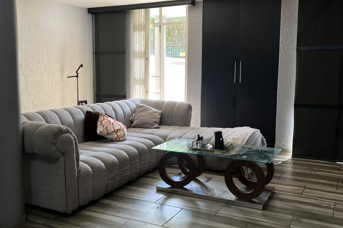 A modern living room featuring wood-look tiled flooring, built-in dark cabinetry, and direct access to an outdoor area through a sliding door.