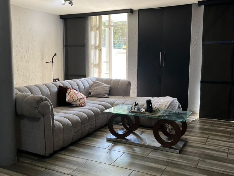 A modern living room featuring wood-look tiled flooring, built-in dark cabinetry, and direct access to an outdoor area through a sliding door.