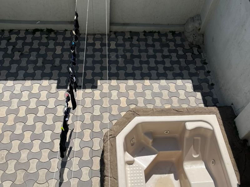 Outdoor paved area featuring a built-in spa and perimeter wall with electric fencing, providing a functional space for relaxation.