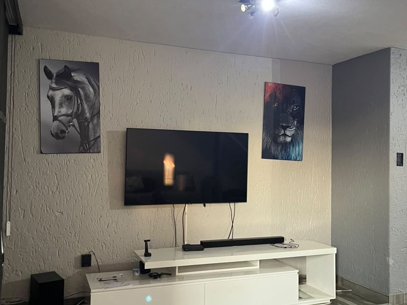 A living room area featuring textured wall finishes, wood-look ceramic floor tiles, and a central spotlight fixture.