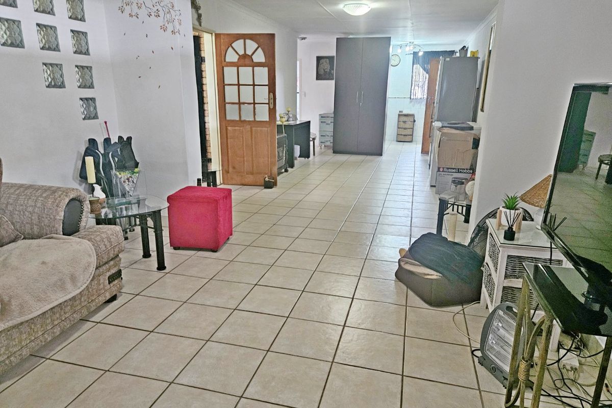 Open plan living area featuring ceramic floor tiles, a glass block feature wall, and direct access to adjacent rooms.