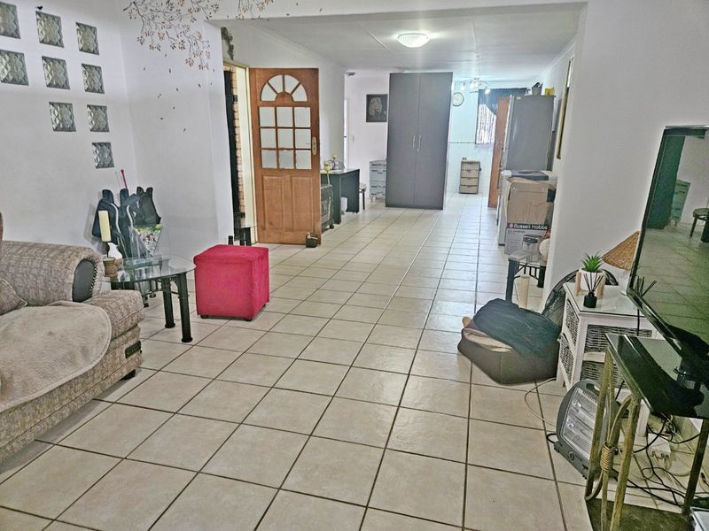 Open plan living area featuring ceramic floor tiles, a glass block feature wall, and direct access to adjacent rooms.