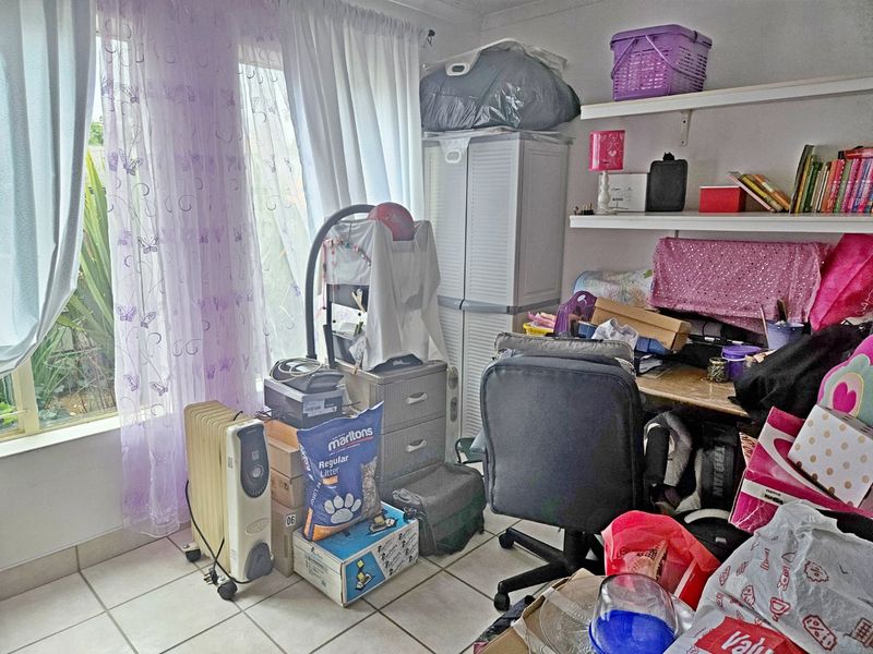 A bedroom featuring tiled flooring and built-in wall shelving, currently utilized as a multi-purpose storage and workspace area.