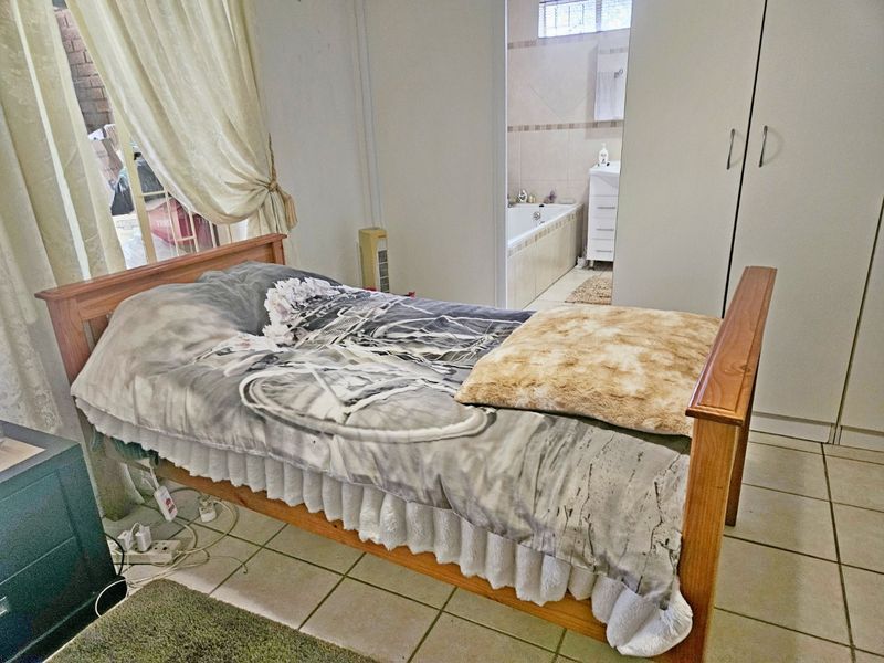 A bedroom featuring tiled flooring and built-in cupboards, with direct access to an en-suite bathroom.