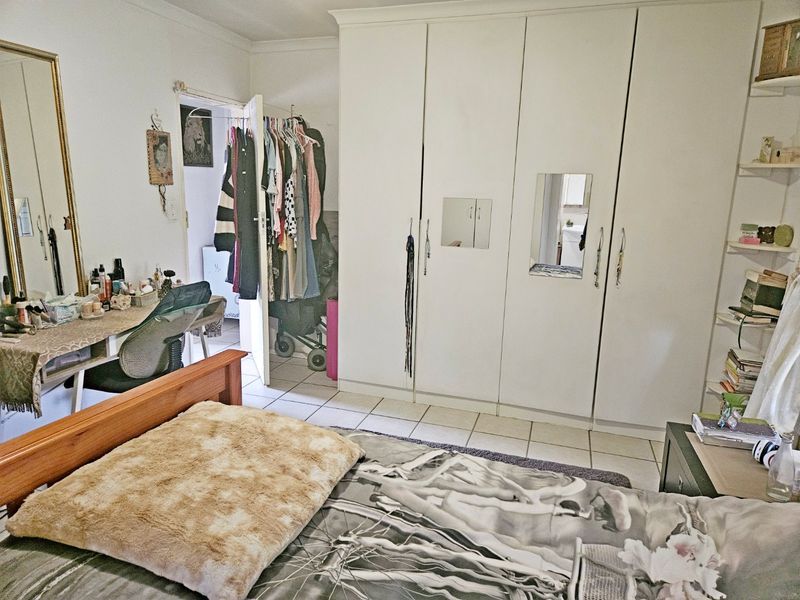 A bedroom featuring built-in cupboards, tiled flooring, and coving, providing a functional space with ample storage.