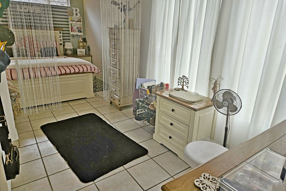 A bedroom featuring tiled flooring and horizontal window blinds, offering a functional space with neutral finishes.
