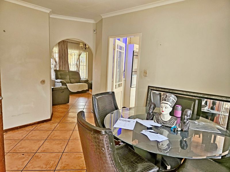 Dining area featuring tiled flooring and an arched entryway leading to an adjacent living space, with neutral wall finishes throughout.