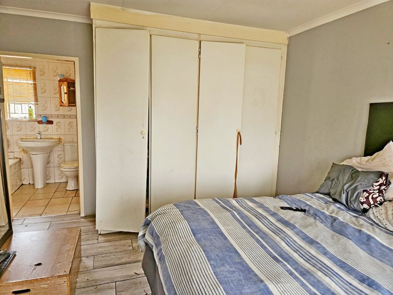 Bedroom featuring built-in cupboards, tiled flooring, and direct access to an en-suite bathroom.