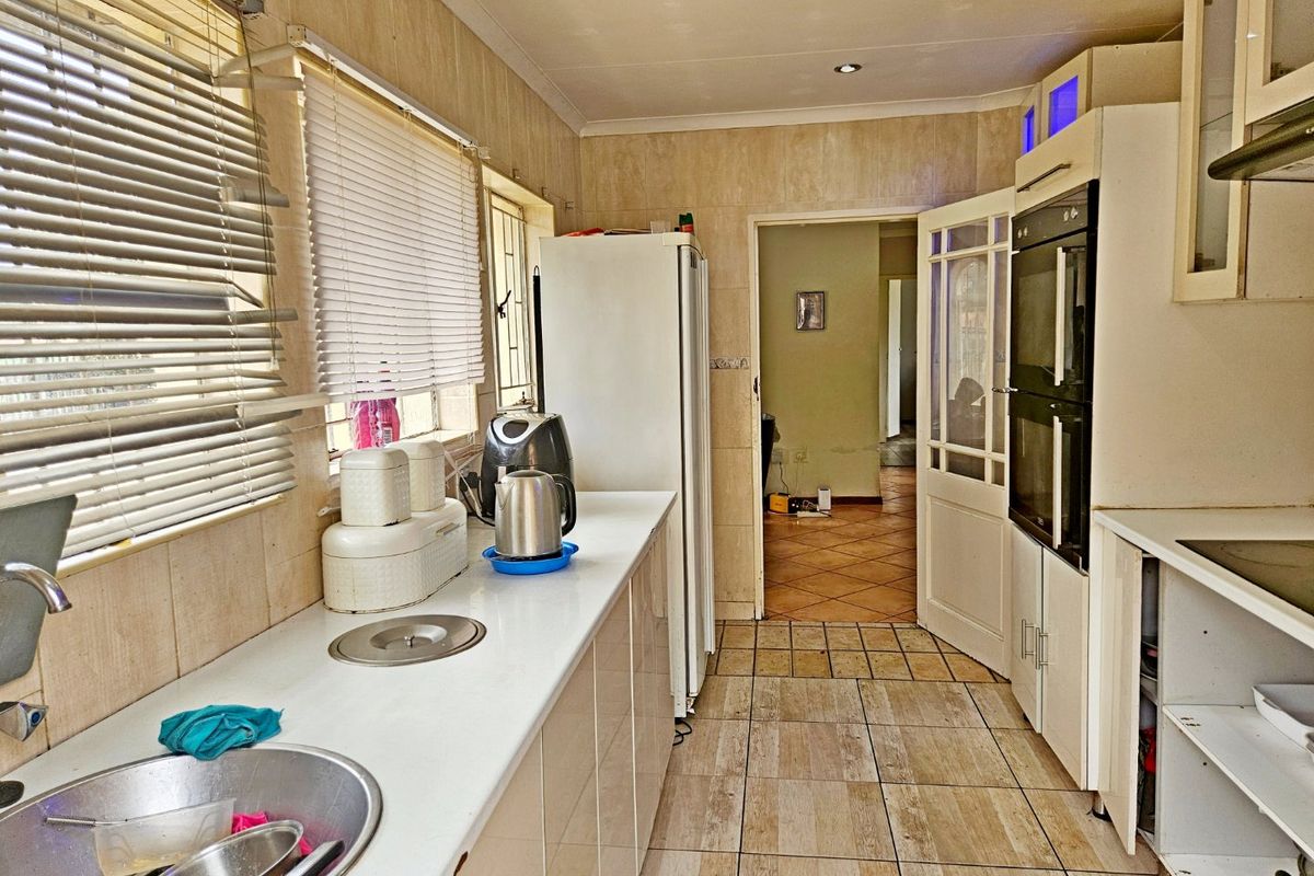A functional kitchen featuring built-in double ovens, tiled surfaces, and ample cabinetry, offering potential for a modern renovation.