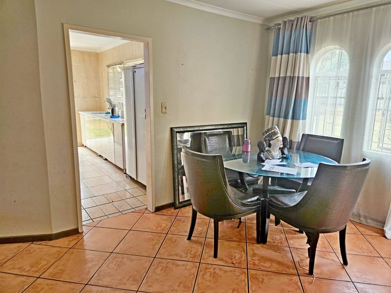 Dining area featuring tiled flooring and an arched window, with an open transition into the adjacent kitchen space.