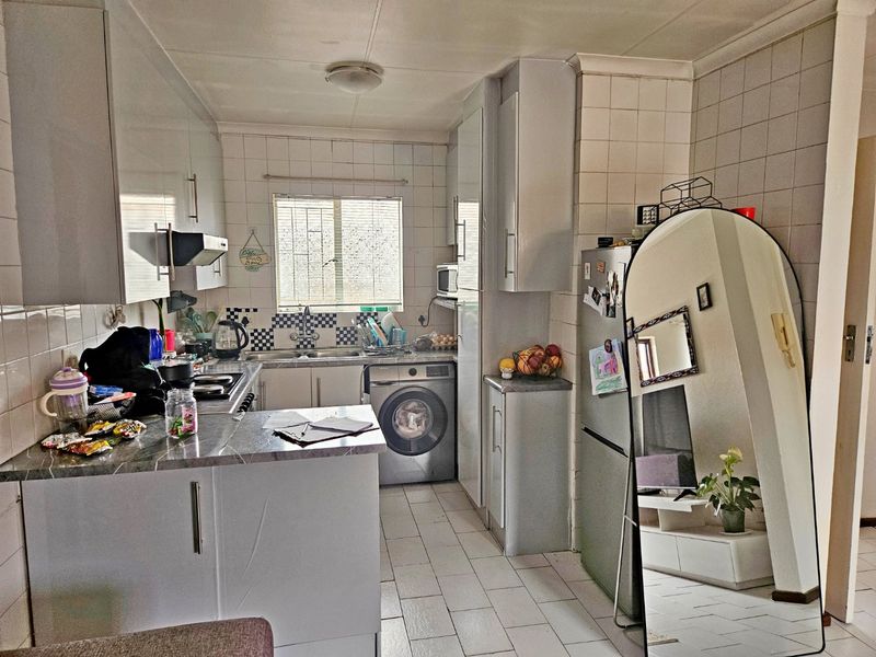 A functional kitchen featuring built-in cabinetry, laminate countertops, a tiled backsplash, and integrated appliances, offering a practical layout for daily meal preparation.