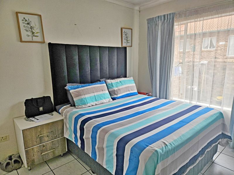 A bedroom featuring tiled flooring and a sliding door with curtain tracks, providing access to the exterior.