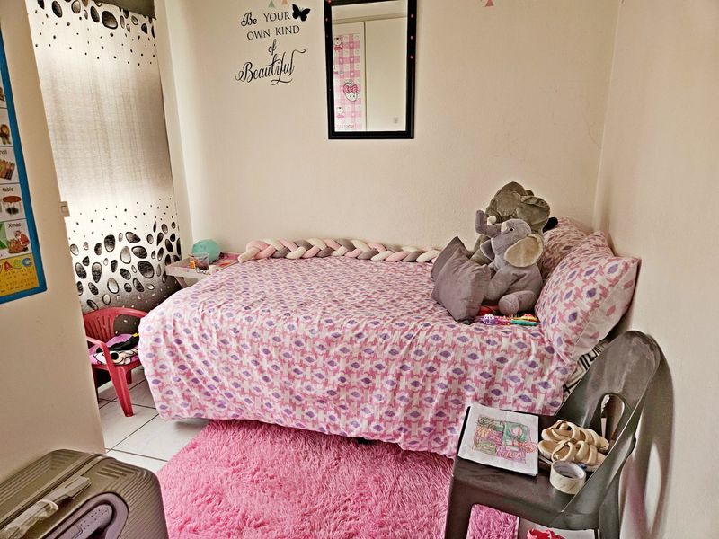 A compact bedroom featuring tiled flooring and a built-in cupboard, providing a functional space for a child or guest.