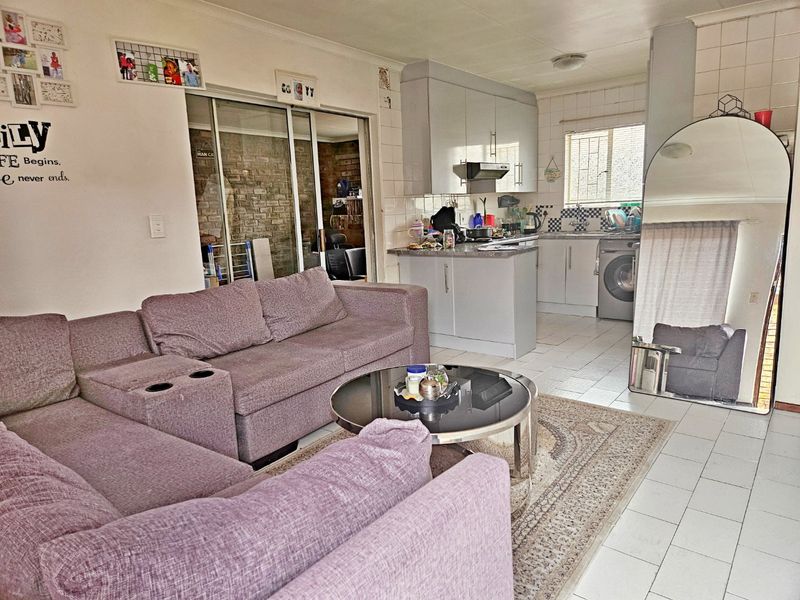 Open-plan living area featuring a combined kitchen with built-in cabinetry and tiled flooring, seamlessly connected to the main living space.