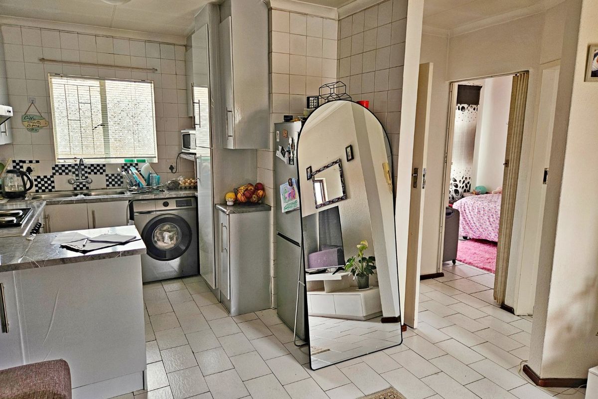 Functional kitchen featuring tiled flooring, built-in cabinetry, integrated laundry plumbing, and a tiled splashback, offering a practical layout for daily meal preparation.