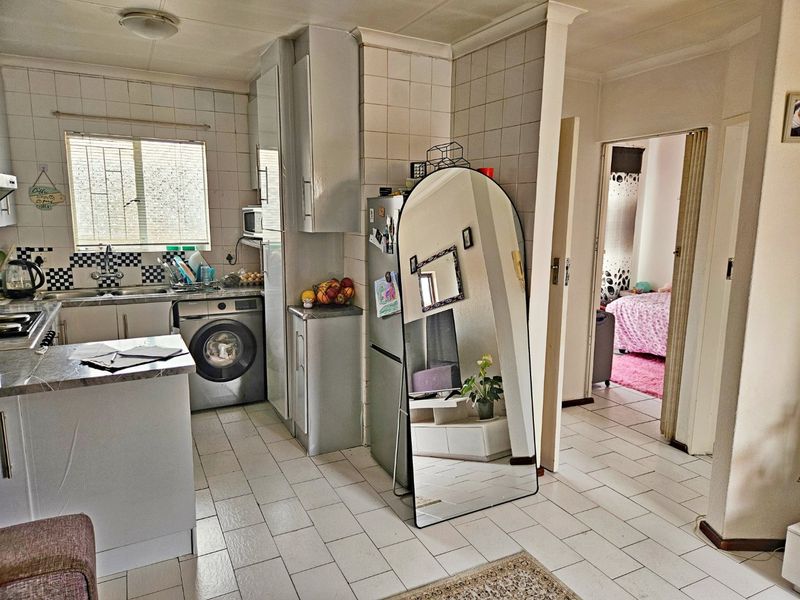 Functional kitchen featuring tiled flooring, built-in cabinetry, integrated laundry plumbing, and a tiled splashback, offering a practical layout for daily meal preparation.