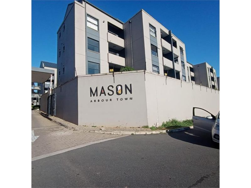 Exterior view of the Mason Arbour Town apartment complex, featuring a secure perimeter wall with electric fencing and paved access.