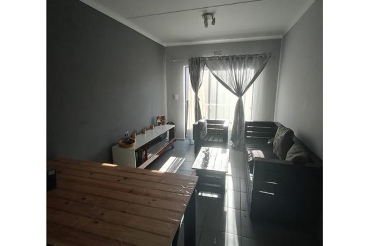 A living room featuring tiled flooring and a sliding glass door that provides natural light and access to the exterior.