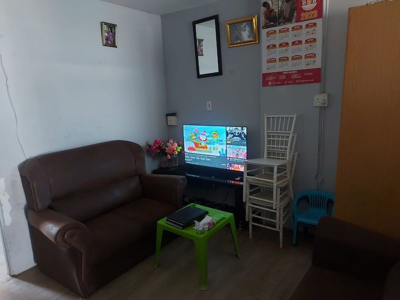 A compact living area featuring laminate flooring and neutral wall finishes, currently utilized as a casual lounge space.