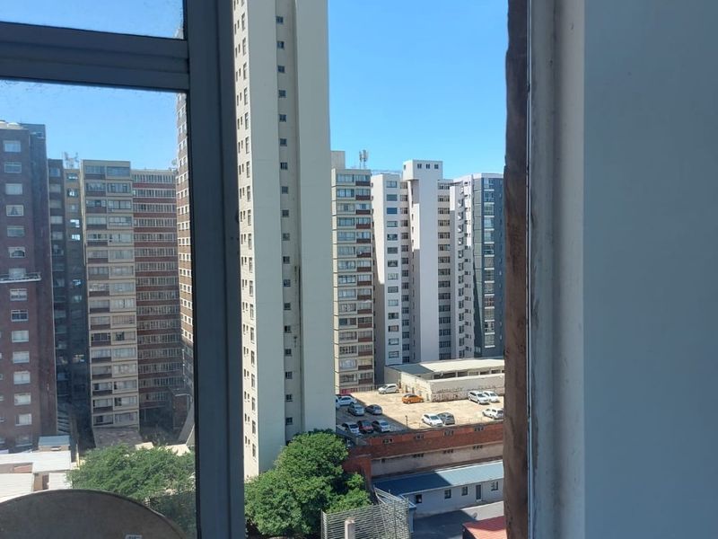 An urban view from an apartment window looking out over surrounding high-rise buildings and a parking area.