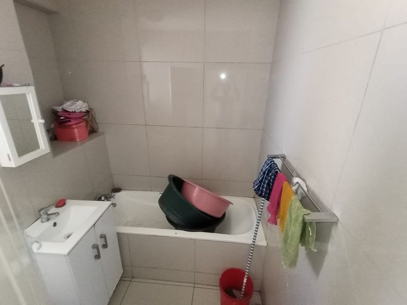 A functional bathroom featuring a bathtub, a vanity cabinet with a basin, and full-height wall tiling.