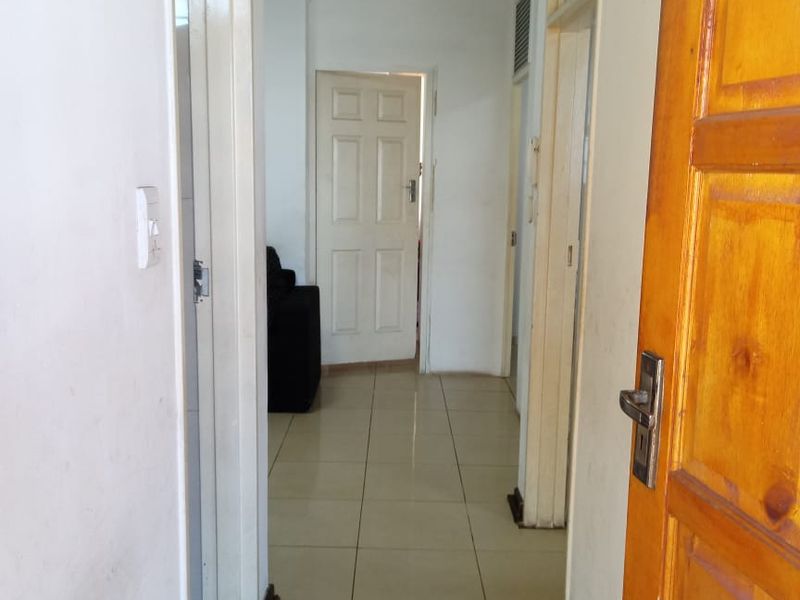 A functional hallway featuring tiled flooring and multiple doorways leading to other rooms within the apartment.