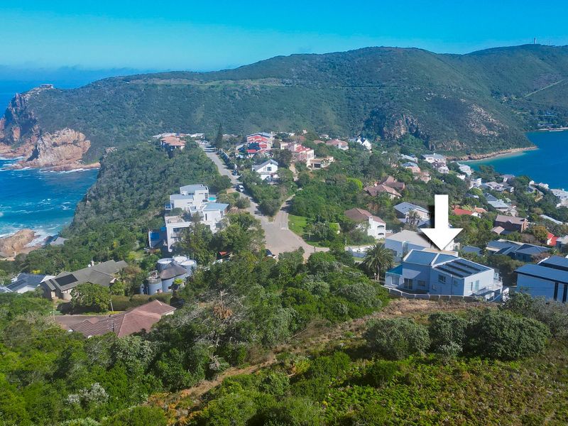 Aerial view of the property situated in a coastal residential estate, featuring solar panels on the roof and surrounding natural landscape.