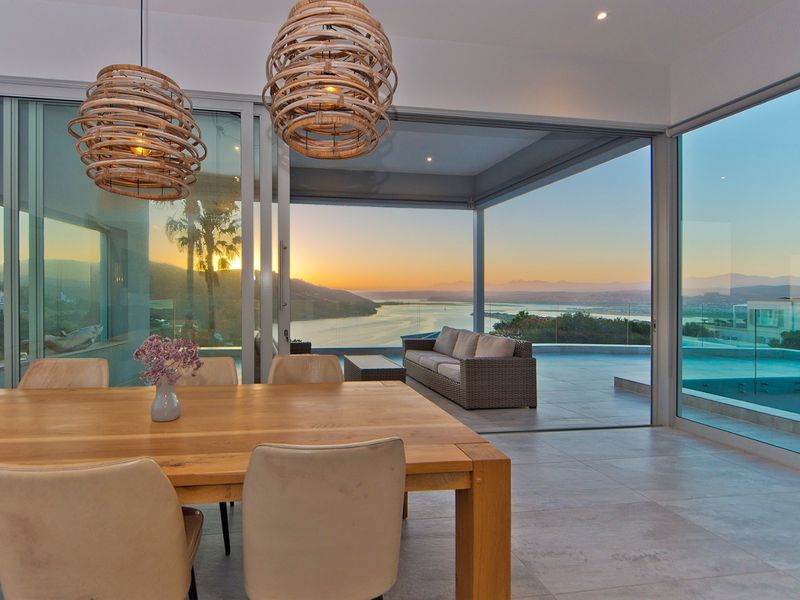 Modern dining area featuring large format floor tiles and expansive sliding glass doors that open to a scenic outdoor patio and water view.