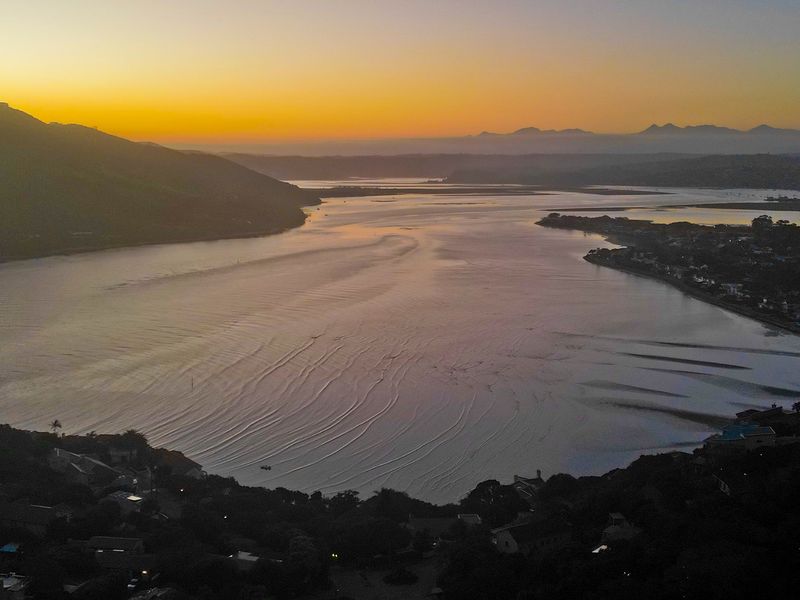 A scenic aerial view of the estuary and surrounding landscape at sunset, showcasing the natural beauty and coastal setting of the property location.