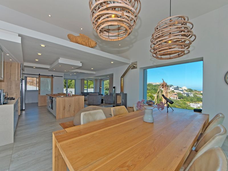 Spacious open-plan living and kitchen area featuring modern cabinetry, a central island, a fireplace, and expansive windows with scenic views.