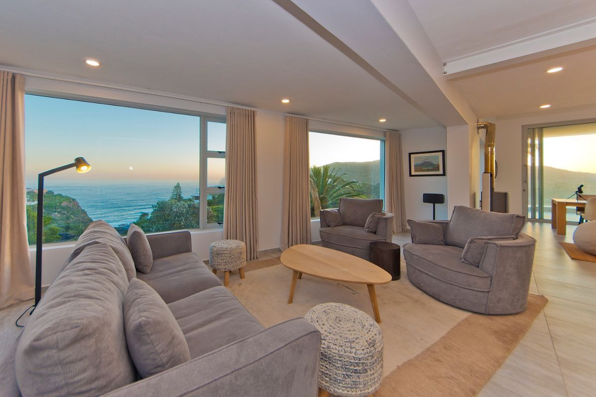 Spacious living room featuring large picture windows with panoramic ocean views, recessed lighting, and a modern freestanding fireplace.