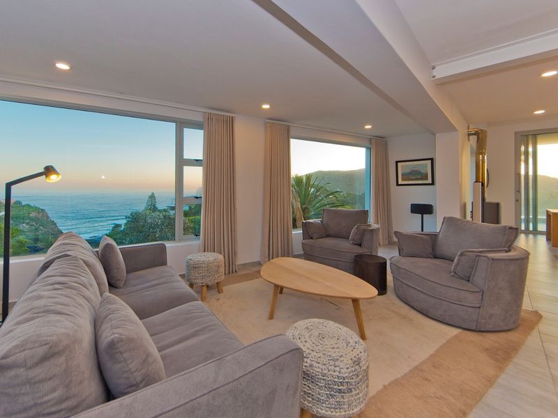 Spacious living room featuring large picture windows with panoramic ocean views, recessed lighting, and a modern freestanding fireplace.