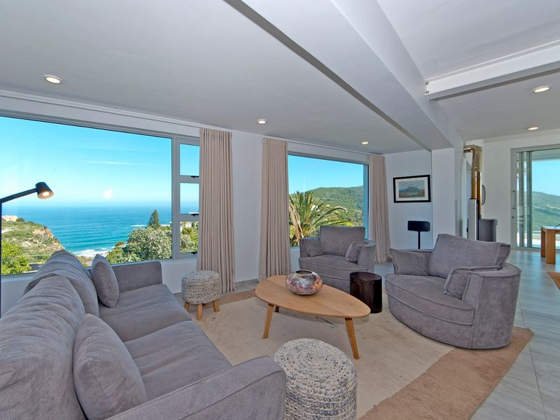 Spacious living room featuring large picture windows with panoramic ocean views, tiled flooring, and a modern freestanding fireplace.