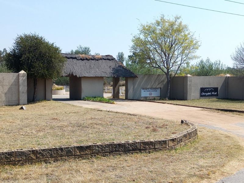 Entrance view of the property featuring a gated access point with a thatched roof structure and perimeter walling.